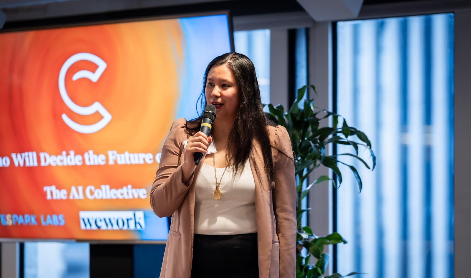 My Luu speaking on stage in front of a screen reading Who Will Decide the Future of Work, The AI Collective